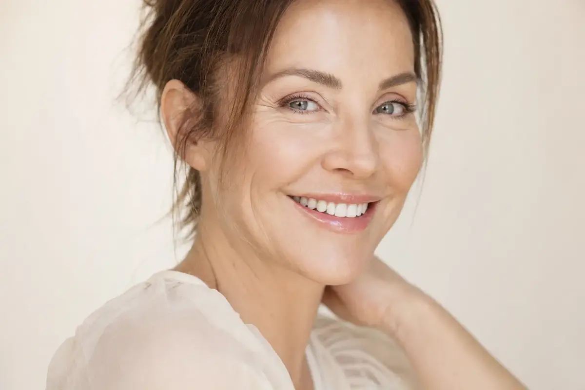 Woman in her forties smiling naturally with soft expression lines around her eyes