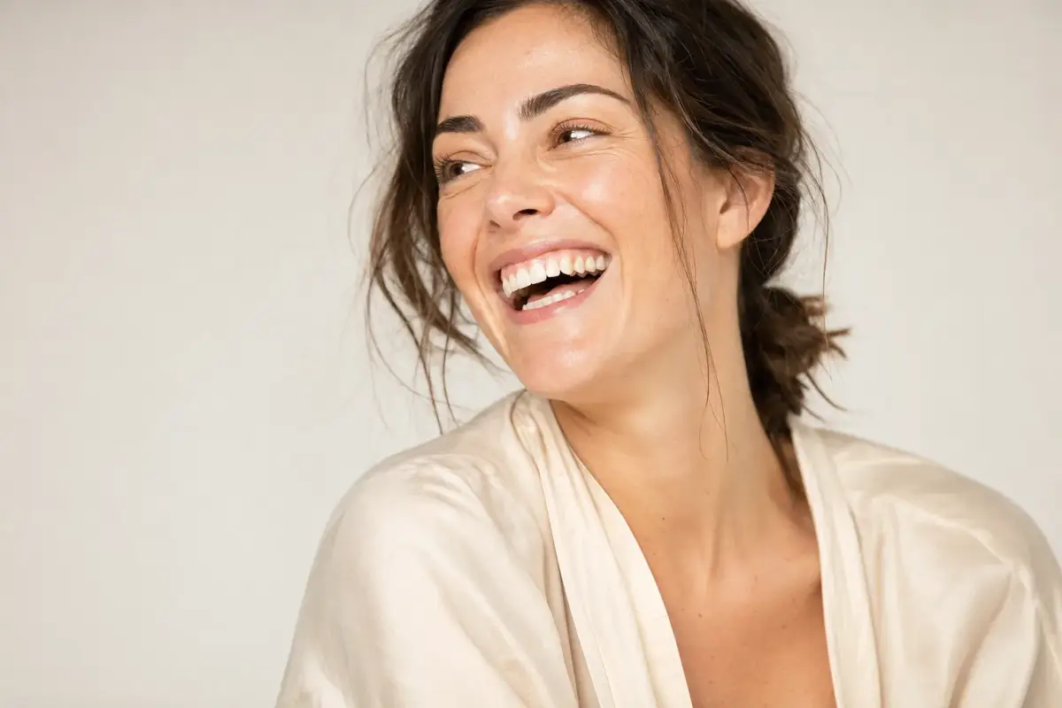 Woman in her thirties mid laugh with natural expression and soft lines
