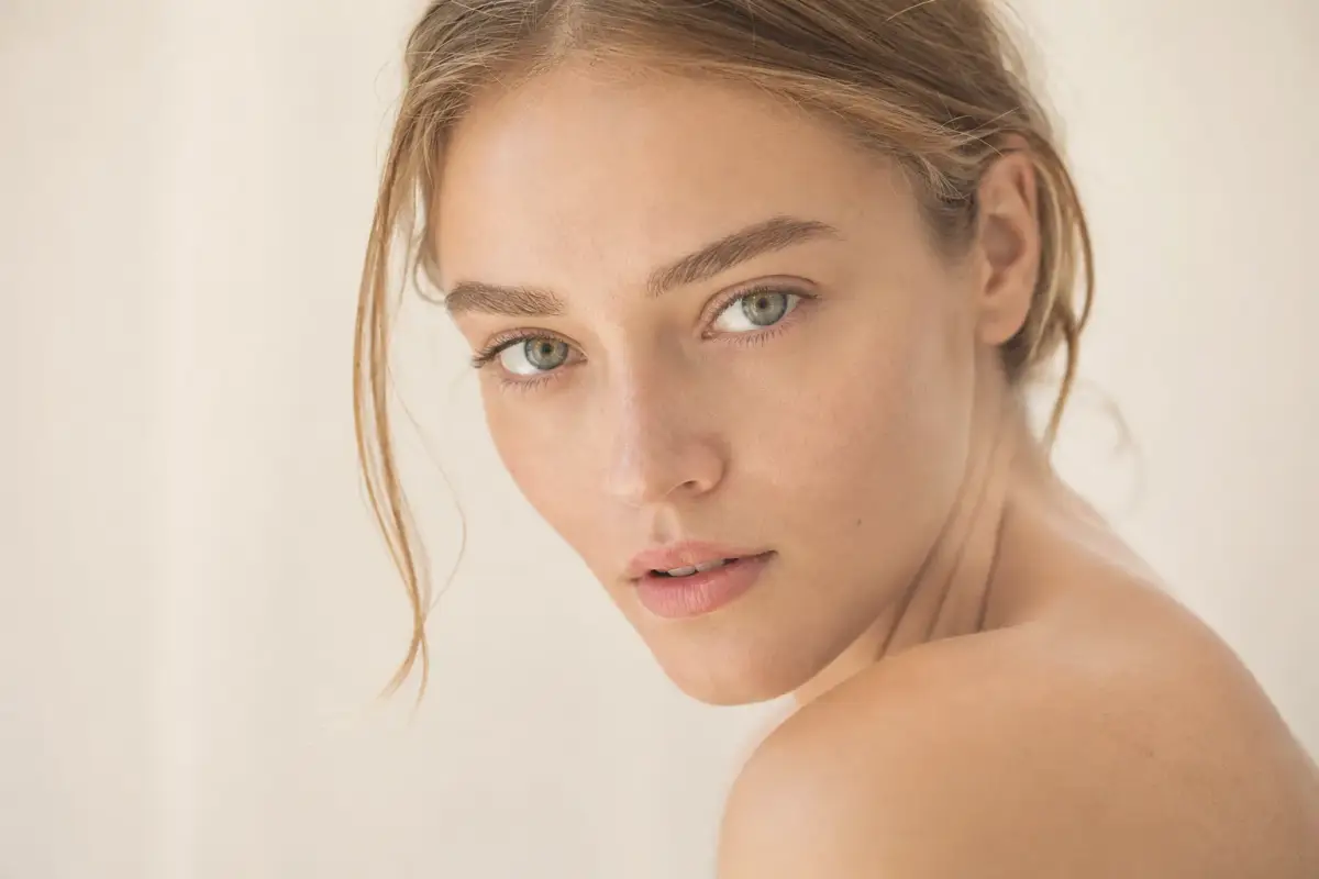 Young woman in her late twenties with natural skin looking at camera with curiosity