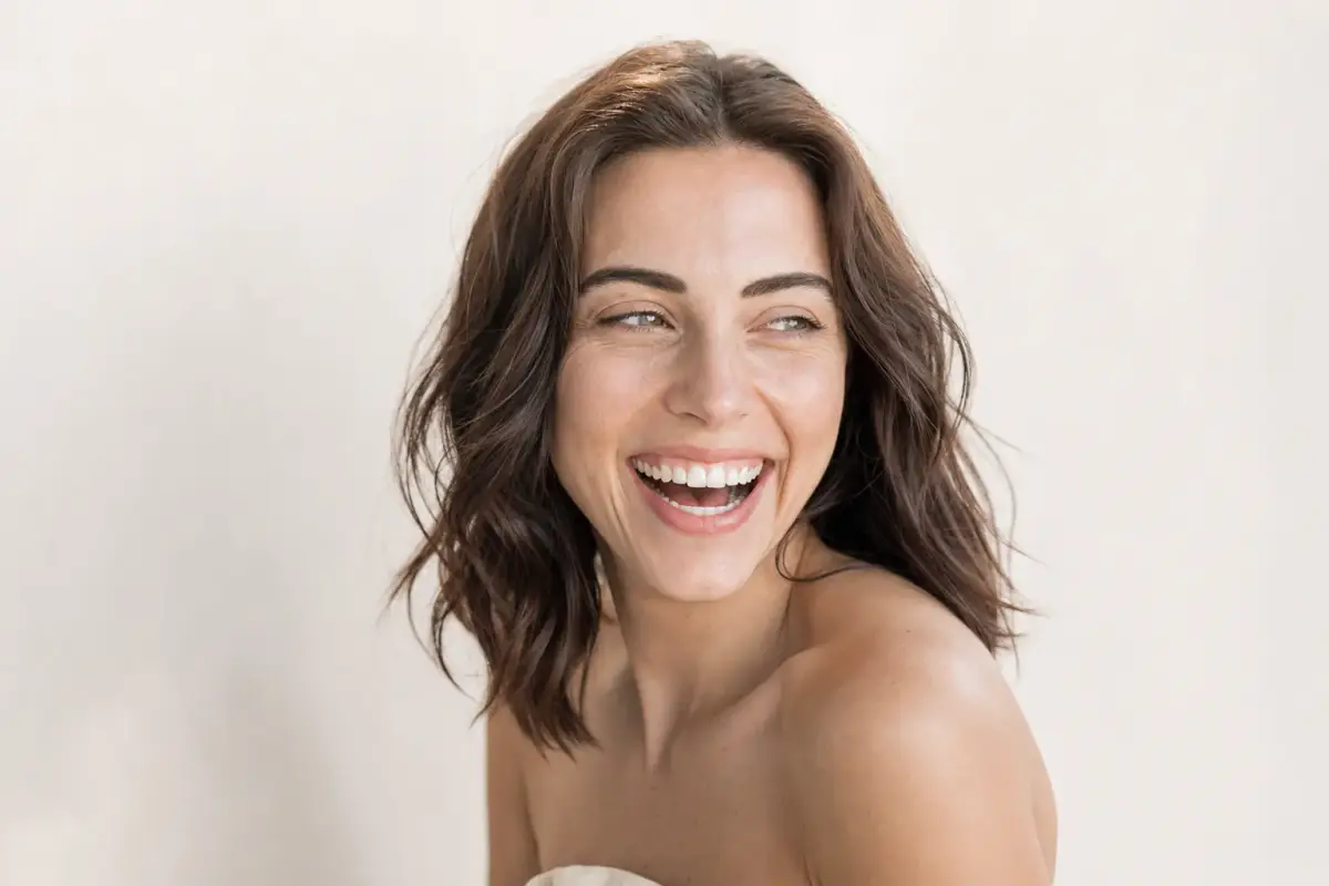 Woman in her thirties with a smooth relaxed forehead laughing lightly