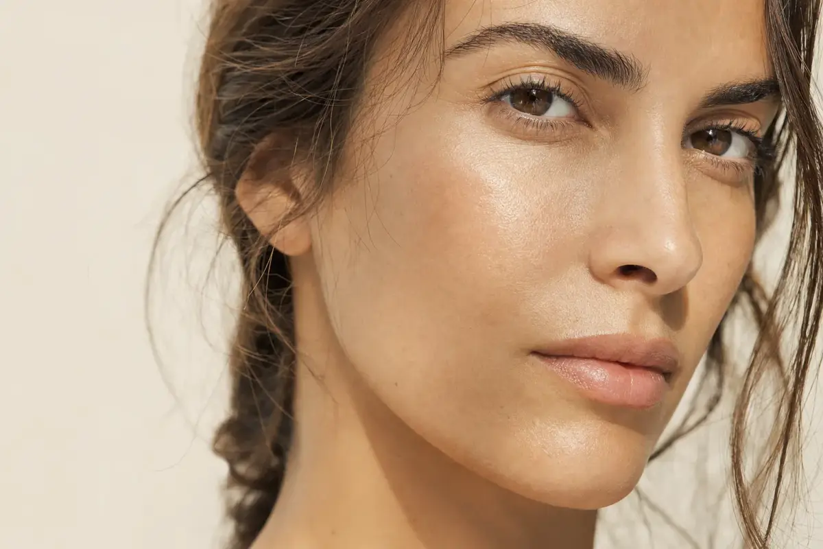 Close-up of a woman in her thirties with Mediterranean skin and an even luminous complexion