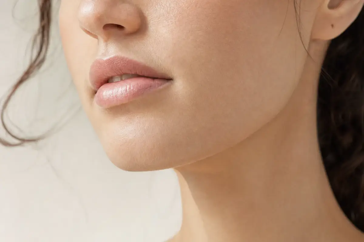 Close-up of the lower face of a woman in her thirties with a slim refined jawline and softened masseter area
